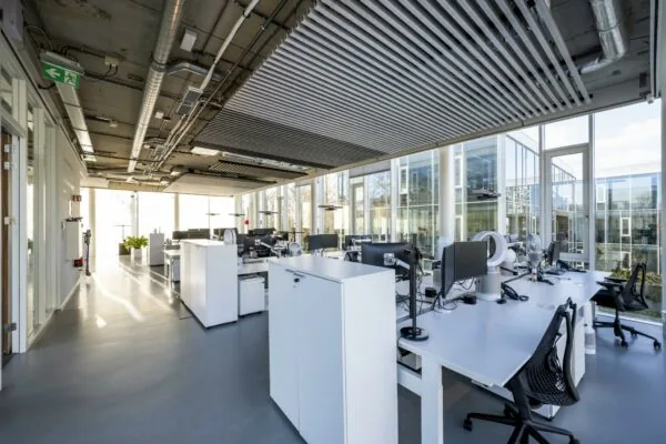 Moderne open kantoorruimte aan de Fred. Roeskestraat met grote ramen, werkplekken en industrieel plafondontwerp.